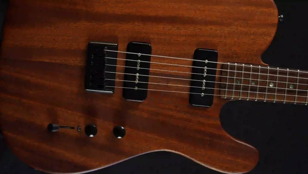 A body of a beautiful mahogany guitar with black hardware and pickups