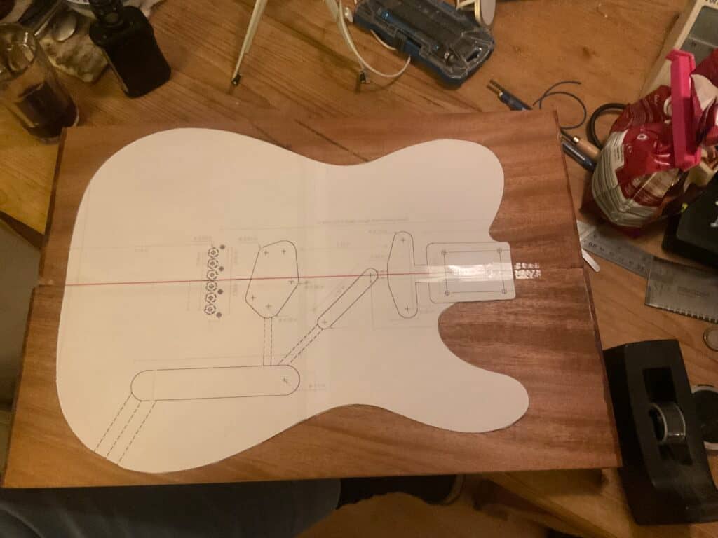 Ein Mahagoniblock mit einer Papierschablone einer elektrischen Gitarre aufgelegt.